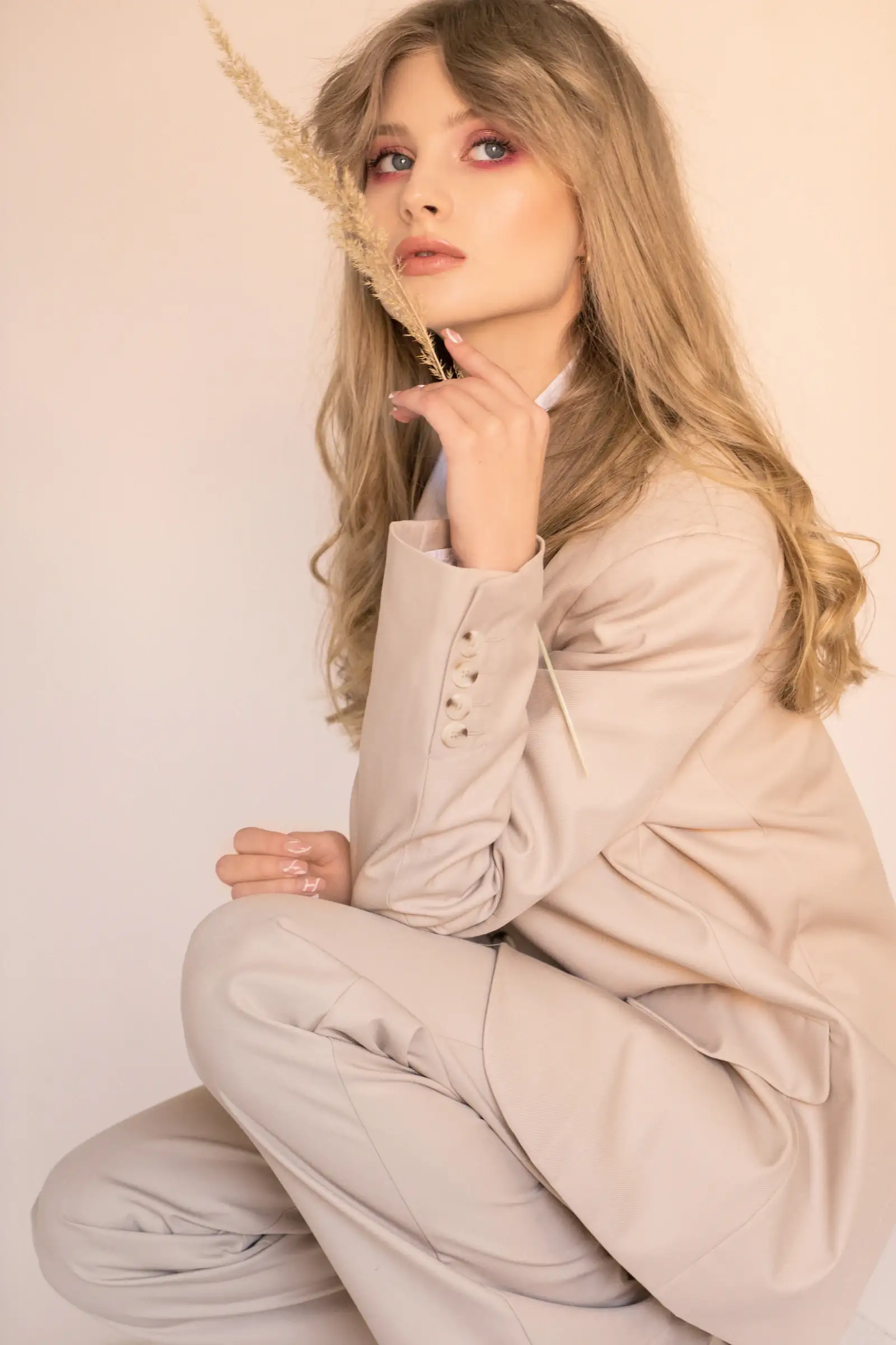 Portrait of Rose in a soft beige suit, hand resting at her chin